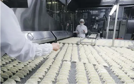  ?? LEE JIN-MAN, THE ASSOCIATED PRESS ?? Workers inspect dumplings on a conveyor belt that are made at an automated factory of CJ CheilJedan­g Corp. in Incheon, South Korea.