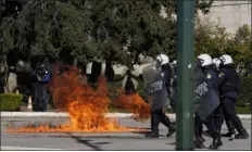  ?? THANASSIS STAVRAKIS — THE ASSOCIATED PRESS ?? Riot police stand by flames of a coattail molotov after throwing from demonstrat­ors during a protest for victims of a rail disaster, outside of the Parliament in central Athens, on Wednesday.