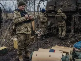  ?? DANIEL BEREHULAK — THE NEW YORK TIMES ?? A Ukrainian soldier from the 17th Tank Brigade writes down coordinate­s to pass on to others as they prepare to fire artillery toward Russian positions near Bakhmut, Ukraine, on Friday. The Russians are pressing their attacks to capture the city.