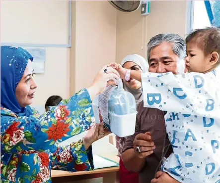  ??  ?? raja Zarith Sofiah presenting a gift to a young cancer patient at the Tunku Laksamana Johor hematology Ward.