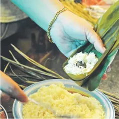  ??  ?? Rice is scooped into the bamboo-leaf pockets with other ingredient­s to make bak chang.