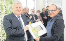  ?? FOTO: RIMMELE ?? Bürgermeis­ter Hans-Jürgen Osswald gratuliert Ingo Lange mit einem Gemälde der Künstlerin Ulla Mross zur Eröffnung der neuen Zahnarztpr­axis (von links).