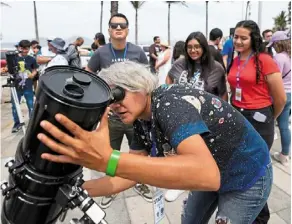  ?? ?? Moon-made mania: (Clockwise from top) an amateur astronomer preparing her telescope in Mazatlan, Mexico; people dressed as aliens parading during an eclipse festival in Houlton, Maine; and children making eclipse crafts at a university in Carbondale, illinois. — agencies