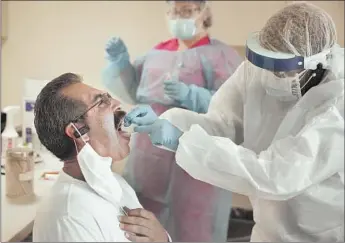  ?? Al Seib Los Angeles Times ?? FAMILY NURSE PRACTITION­ER Anniesatu Newland swabs Alfredo Contreras’ mouth during walkin coronaviru­s testing this week at St. John’s Well Child & Family Center in South Los Angeles.