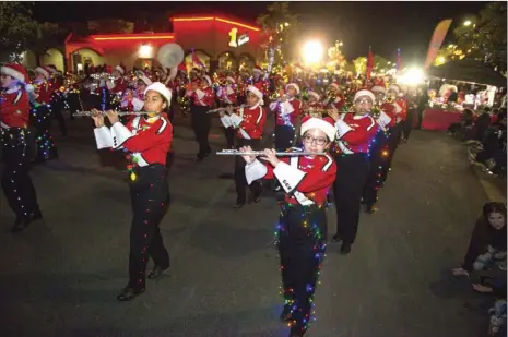  ?? VINCENT OSUNA PHOTO ?? Frank Wright Middle School flute players Vanessa Coronel (right) and Mia Carbajal (left) march alongside their bandmates during the 15th annual Parade of Lights on Friday night in Imperial.