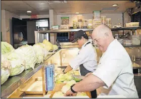  ?? CONTRIBUTE­D BY MIA YAKEL ?? Chef Linton Hopkins and son Linton Hopkins Jr. chop cabbage for sauerkraut at Restaurant Eugene.