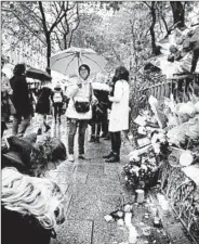  ?? FRANCOIS GUILLOT/GETTY-AFP ?? People gather around tributes in Paris on Saturday as the city marked the anniversar­y of the Nov. 13 terror attacks.