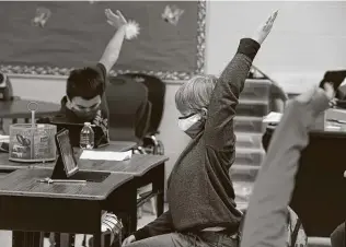  ?? Kin Man Hui / Staff file photo ?? Third grader Logan Sapp, center, raises his arm to answer a question as students in the third grade at Pearce Elementary School in Southside ISD participat­e in online and in-person learning. Texas public schools have seen enrollment drop 3 percent on average this school year.