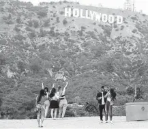  ?? Mario Tama / Getty Images ?? People take photos in front of the famed Hollywood sign in Los Angeles on Oct. 7. A strike by behind-the-scenes workers would be a serious setback for the entertainm­ent industry.