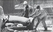  ??  ?? Oakland Public Works Department employees remove a couch as they clean a homeless camp in Oakland.