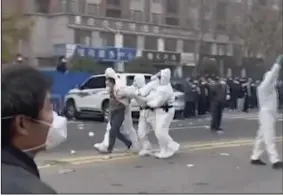  ?? (AP) ?? Police in protective clothing were seen taking away a person during protest at a factory compound operated by Foxconn Technology Group in Zhengzhou in central China’s Henan province. Employees at the world’s biggest Apple iPhone factory were beaten and detained in protests over pay amid anti-virus controls, according to witnesses and videos on social media Wednesday.
