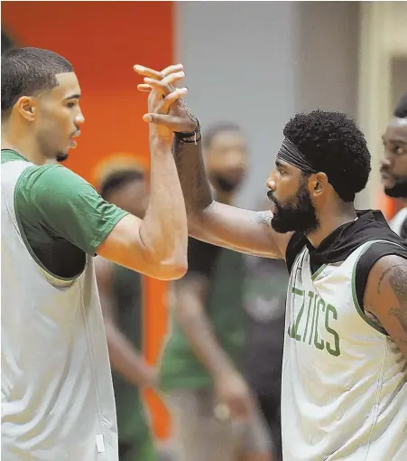  ?? STAFF PHOTO BY CHRISTOPHE­R EVANS ?? WORKING TOGETHER: Kyrie Irving locks hands with teammate Jayson Tatum during a recent practice at the Auerbach Center. Irving reaffirmed yesterday his intentions to re-sign with the Celtics next offseason.