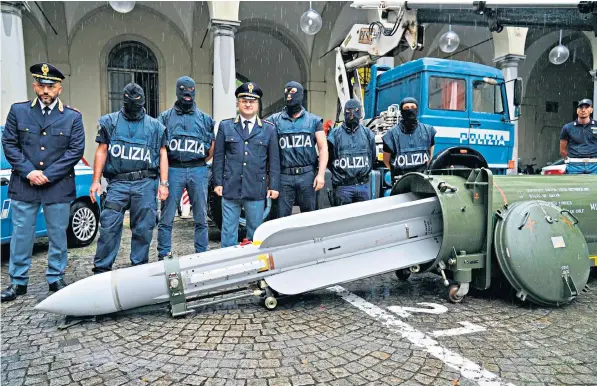  ??  ?? Police, some keeping their identities secret, pose with a missile seized at an airport hangar near Pavia, northern Italy, following an investigat­ion into Italians who took part in the Russian-backed insurgency in eastern Ukraine