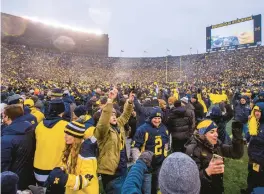  ?? TONY DING/AP ?? Michigan fans celebrate on the field after the team’s win over Ohio State in Ann Arbor, Mich., in 2021.