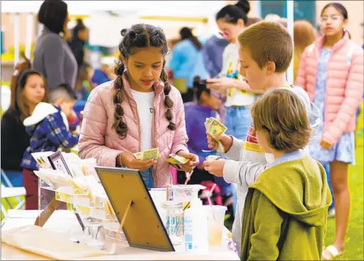  ?? NELVIN C. CEPEDA U-T PHOTOS ?? Darielyz Talavera, 11, from Point Loma, sells custom decorated cookies to a customer at the San Diego Children’s Business Fair held Saturday at Liberty Station.