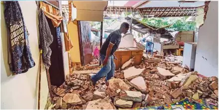  ??  ?? A man walking among debris in a damaged house in Lombok, Indonesia, yesterday.
