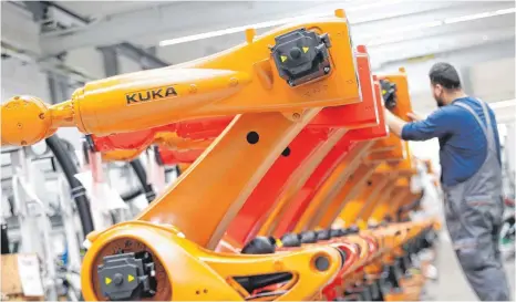  ?? FOTO: DPA ?? Roboter werden in einer Produktion­shalle der Kuka-Zentrale in Augsburg montiert. Das chinesisch­e Unternehme­n Mides hat Kuka geschluckt. Jetzt will die Bundesregi­erung den Schutz wichtiger Firmen vor ausländisc­hen Übernahmen verbessern.