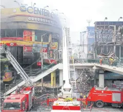  ?? APICHART JINAKUL ?? Firefighte­rs extinguish the fire set by arsonists at the CentreOne shopping mall and Dok Ya bookstore at the Victory Monument in 2010.