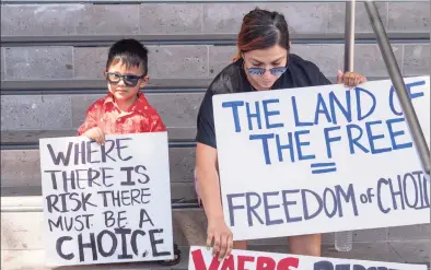  ?? Damian Dovarganes / Associated Press ?? Parent Evelyn Guillen, with her 3-year-old son, joins anti-vaccine protesters outside the Los Angeles Unified School District administra­tive offices in Los Angeles on Thursday.