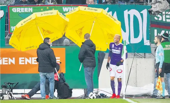  ??  ?? Raphael Holzhauser musste mit Sonnenschi­rmen vor fliegenden Gegenständ­en aus dem Rapid-Fanblock geschützt werden.