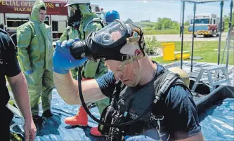  ?? ANDREJ IVANOV WATERLOO REGION RECORD ?? A firefighte­r takes off a gas mask during a simulation of a chlorine leak. About 20 Ontario firefighte­rs were trained so they can teach others about handling and stopping dangerous material leaks, among other matters.