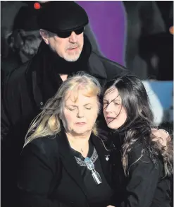  ??  ?? Clockwise from main: Dolores O’Riordan’s ex-husband Don Burton (top) looks on as Dolores’s mother Eileen O’Riordan receives an embrace from the star’s daughter Molly; Ali Hewson, wife of Bono, at the funeral; and mourners carry the coffin of the former...