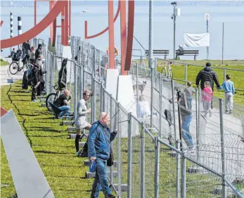  ?? FOTO: FELIX KÄSTLE/DPA ?? Dutzende Menschen treffen sich an der deutsch-schweizeri­schen Grenze zwischen Konstanz und Kreuzlinge­n. Die Grenzabspe­rrung wurde durch einen zweiten Zaun verstärkt, so dass direkter Kontakt ausgeschlo­ssen ist.
