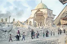  ??  ?? Civiles iraquíes desplazado­s caminan sobre los restos de las mezquita al-Nuri, mientras las fuerzas del gobierno combaten al Estados Islámico.