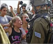  ?? AP 2012 ?? Ahed Tamimi, as a 12-year-old, raises a clenched fist toward a soldier towering over her in 2012, one of her several highly publicized run-ins with soldiers.