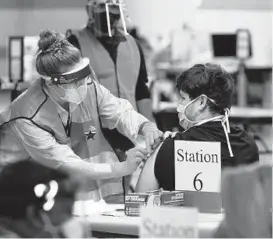  ?? ERIC GAY/AP ?? A health care worker administer­s a COVID-19 vaccinatio­n Monday at the new Alamodome COVID-19 vaccine site in San Antonio. Officials say the site is providing 1,500 vaccinatio­ns per day as cities and states across the nation are ramping up efforts.