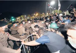  ?? SAKCHAI LALIT/AP ?? Pro-democracy protesters pull steel barricades in front of police as they try to march forward during a demonstrat­ion Saturday in Bangkok.