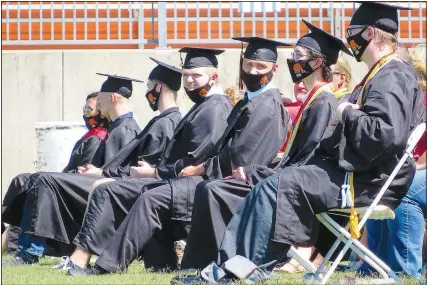  ??  ?? Gravette seniors wait for their row to be called to receive diplomas during the ceremony. Though the telephoto lens makes it appear they were sitting side-by-side, they were actually spaced apart to comply with social distancing guidelines.