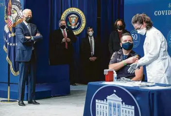  ?? Saul Loeb / AFP via Getty Images ?? President Joe Biden watches as nurse Elizabeth Galloway administer­s a COVID-19 vaccine to firefighte­r Corey Hamilton during an event marking the 50 millionth dose administer­ed since Biden was sworn in.