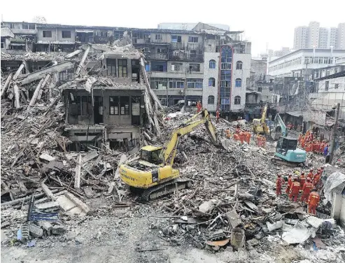  ?? AFP / GETTY IMAGES ?? Rescuers search four collapsed buildings in Wenzhou, China on Monday. A series of multi-storey buildings built by local villagers fell in, killing 22 people, including the father of a toddler who survived because of his protective embrace.