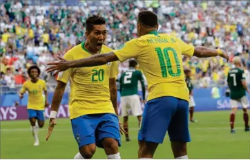  ?? AP PHOTO BY ANDRE PENNER ?? Brazil’s Roberto Firmino, left, celebrates with Brazil’s Neymar, right, after scoring his side’s second goal during the round of 16 match between Brazil and Mexico at the 2018 soccer World Cup in the Samara Arena, in Samara, Russia.