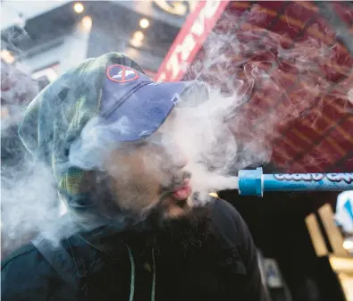  ?? JOHN MINCHILLO/AP ?? A smoker inhales from a “Cloud Cannon” on Jan. 24 outside Smacked, a pop-up cannabis dispensary in New York.