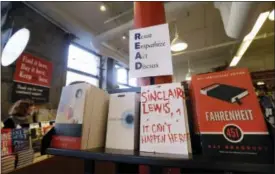  ?? ELISE AMENDOLA — THE ASSOCIATED PRESS ?? Books are displayed under a sign at the Harvard Book Store, Thursday in Cambridge, Mass. Readers have been flocking to classic works of dystopian fiction in the first months of Donald Trump’s presidency. Novels depicting dysfunctio­nal societies have...