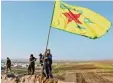  ?? Foto: dpa ?? Mitglieder der kurdischen Miliz YPG his sen ihre Flagge.