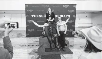  ?? Ashley Landis / Dallas Morning News ?? Crystal Perkins, executive director of the Texas Democratic Party, and convention director Adam Goodrum pose with Norman the bull before an opening reception Thursday in Fort Worth.