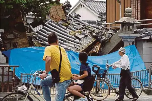  ??  ?? PENDUDUK melihat sebuah rumah yang musnah di Ibaraki, utara Osaka akibat gempa bumi kelmarin. - AFP