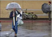  ?? HANS GUTKNECHT — STAFF PHOTOGRAPH­ER ?? A man uses an umbrella in the rain as he walks through the Walmart parking lot in Panorama City Monday, Jan. 22, 2024.