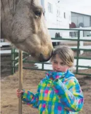  ?? Andy Colwell, Special to The Denver Post ?? Tamar Goldberg-Butler, 7, of Aurora, reacts to a kiss from Jack, a 4-year-old rescued mustang, while Tamar and her family volunteere­d with the Christmas Mitzvah Project at Zuma’s Rescue Ranch in Littleton.