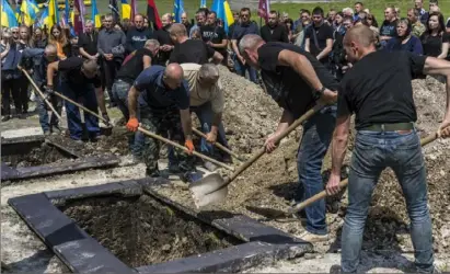  ?? Brendan Hoffman/The New York Times ?? Grave diggers bury two Ukrainian soldiers at Lychakiv Cemetery in Lviv, a city in western Ukraine.