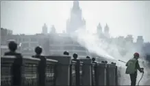  ?? ALEXANDER NEMENOV / AFP ?? A worker disinfects an embankment fence in front of the Moscow State University on Saturday.