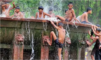  ?? — BUNNY SMITH ?? Children play at a water fountain near India Gate in New Delhi on Saturday. It was a sultry morning in the national capital on Saturday morning with the weatherman predicting dust storm accompanie­d by squall towards the night.