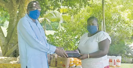  ??  ?? St James Custos Bishop Conrad Pitkin presents a gift of 100 face masks to Cordell Howell-Huie, the administra­tor of the Mustard Seed Children’s Home in Adelphi, St James. Fortyeight lunches from Burger King were also bought for the home’s children, courtesy of the Janet Richards Foundation.