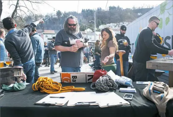  ?? Stephanie Strasburg/Post-Gazette ?? Gear Fest co-founder Christine Iksic talks with Paul Pistella of Millvale while collecting used outdoors gear Sunday at Grist House Craft Brewery in Millvale. The goods will be sold on consignmen­t at Gear Fest.