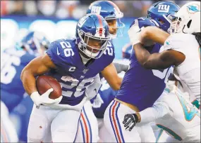  ?? Adam Hunger / Associated Press ?? New York Giants running back Saquon Barkley (26) runs with the ball in the second half against the Miami Dolphins on Sunday in East Rutherford, N.J.