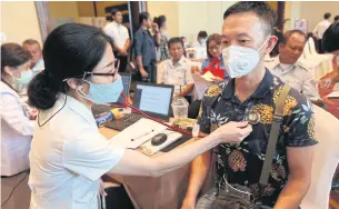  ?? VARUTH HIRUNYATHE­B ?? A medical check-up is offered to a taxi driver by a healthcare practition­er. Several insurance firms have stopped selling pandemic policies.