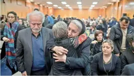  ?? — AP ?? Forough Hamidi (centre right) is embraced by a woman as she and her husband Ahmad Ahmadi (L) whose nephew died in a Ukraine airplane crash in Iran, attend a vigil for the victims of the flight at the Har El Synagogue in West Vancouver, British Columbia